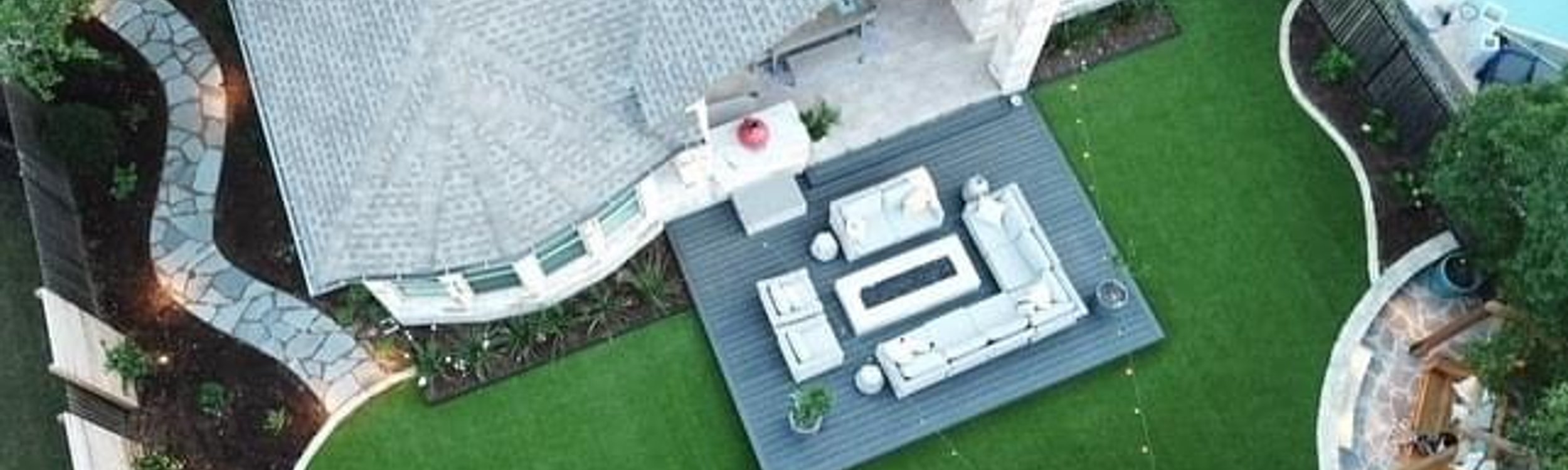Aerial view of a composite deck with turf and a flagstone patio in a Bee Cave backyard