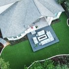 Aerial view of a backyard deck with a flagstone patio and turf under mature live oaks in Bee Cave, near Austin