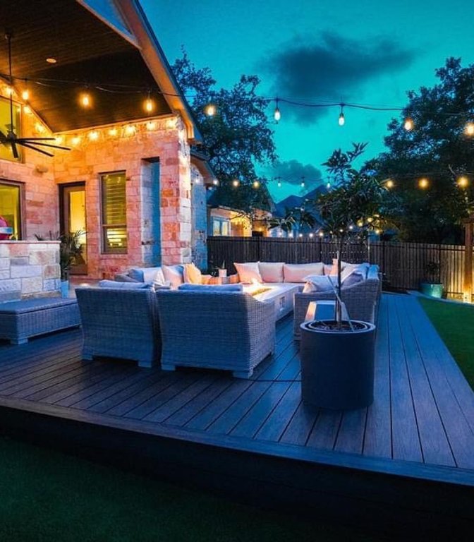 Backyard redesigned with layered warm landscape lighting at night in Bee Cave