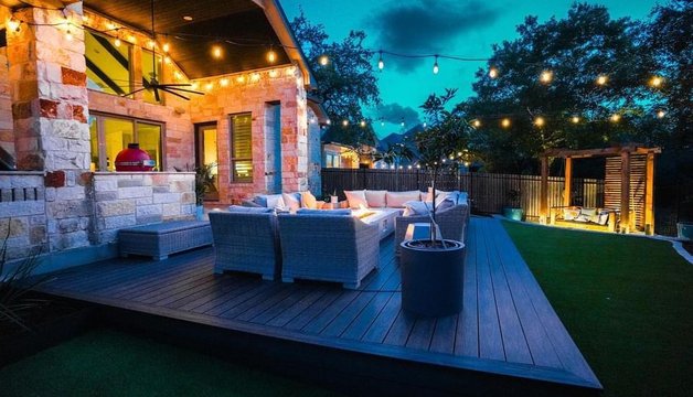 Lighting design with string lights over a Bee Cave deck, pergola, and fire pit at night