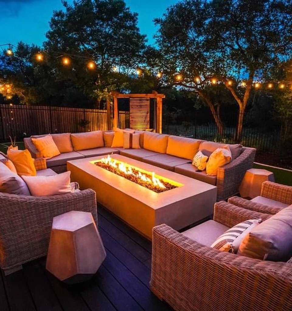 Bee Cave fire pit lit at night beside a privacy screen and string lights