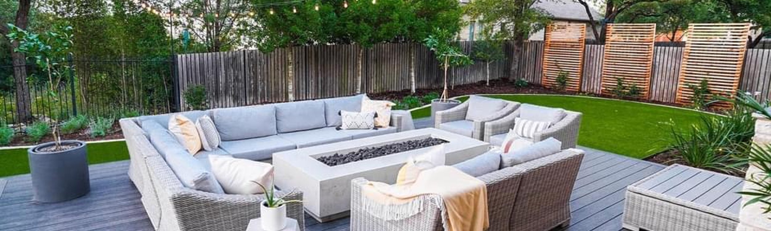 Tall cedar privacy screen wrapping a Bee Cave backyard with a deck, firepit, and turf