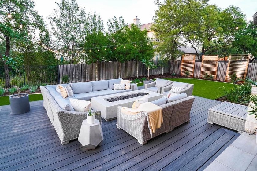 Cedar slat privacy screens rising above a wood fence beside a composite deck and fire table in a Bee Cave backyard