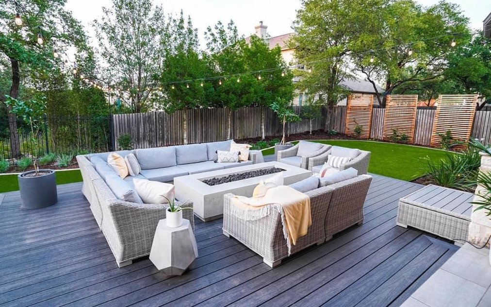Cedar slat privacy screens rising above a wood fence beside a composite deck and fire table in a Bee Cave backyard