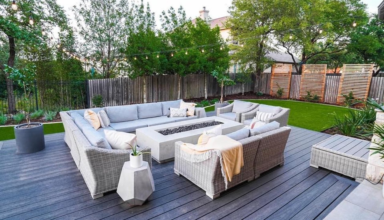 Backyard fire pit on a deck with turf, privacy screens, and planters in Bee Cave
