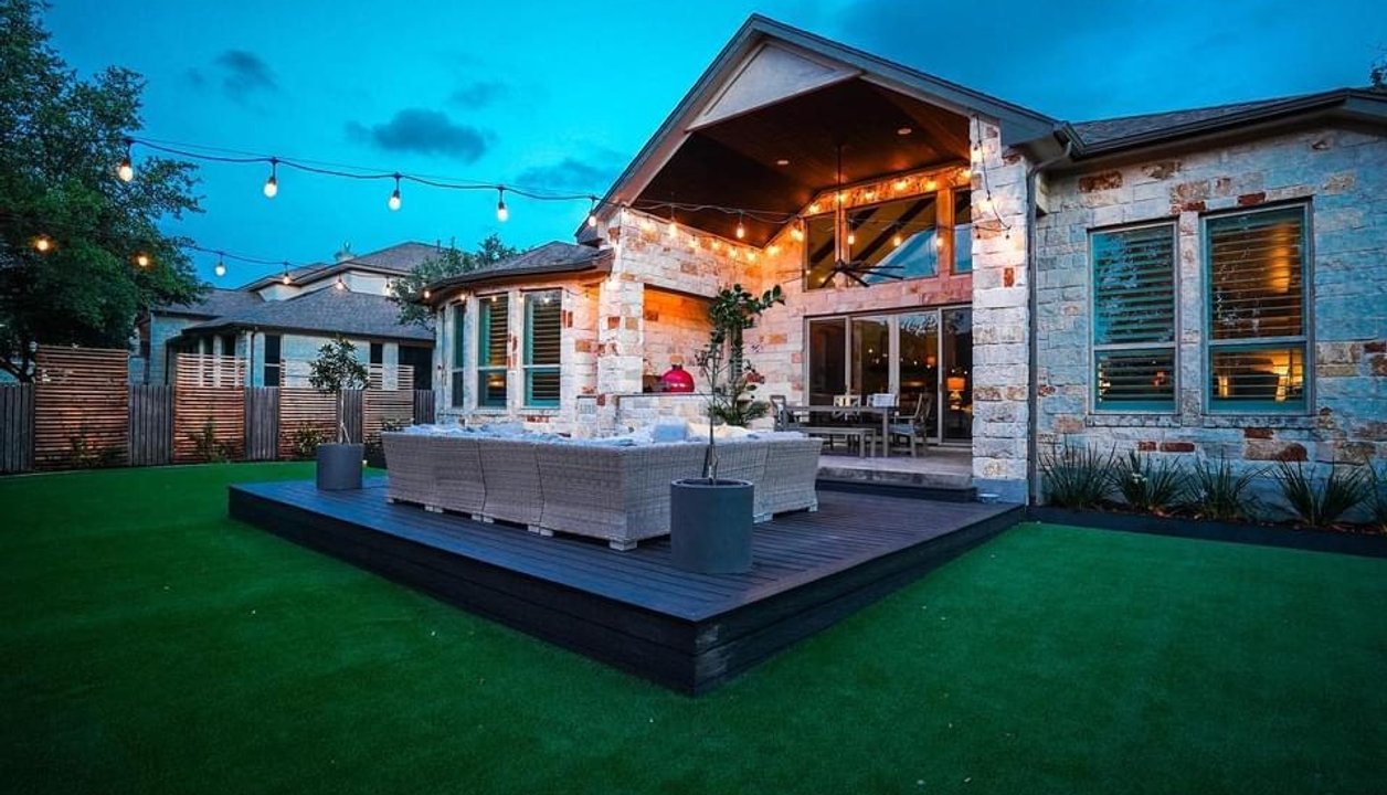 Custom-built deck with string lights and turf in a Bee Cave backyard