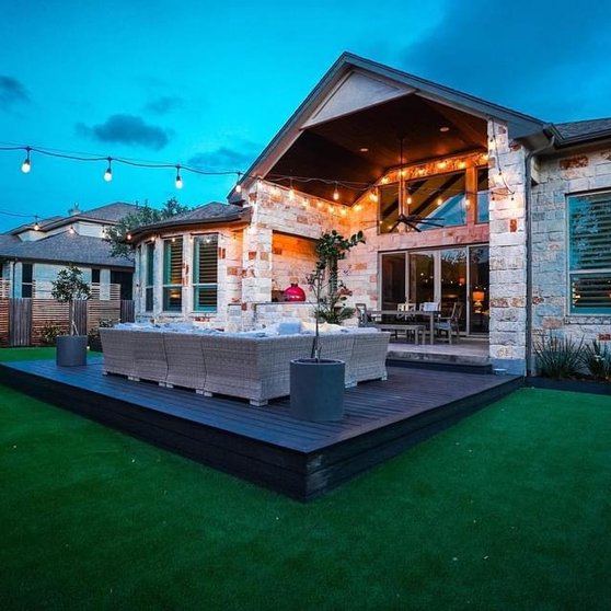 Turf lawn beside a deck and patio with string lights at a Bee Cave backyard