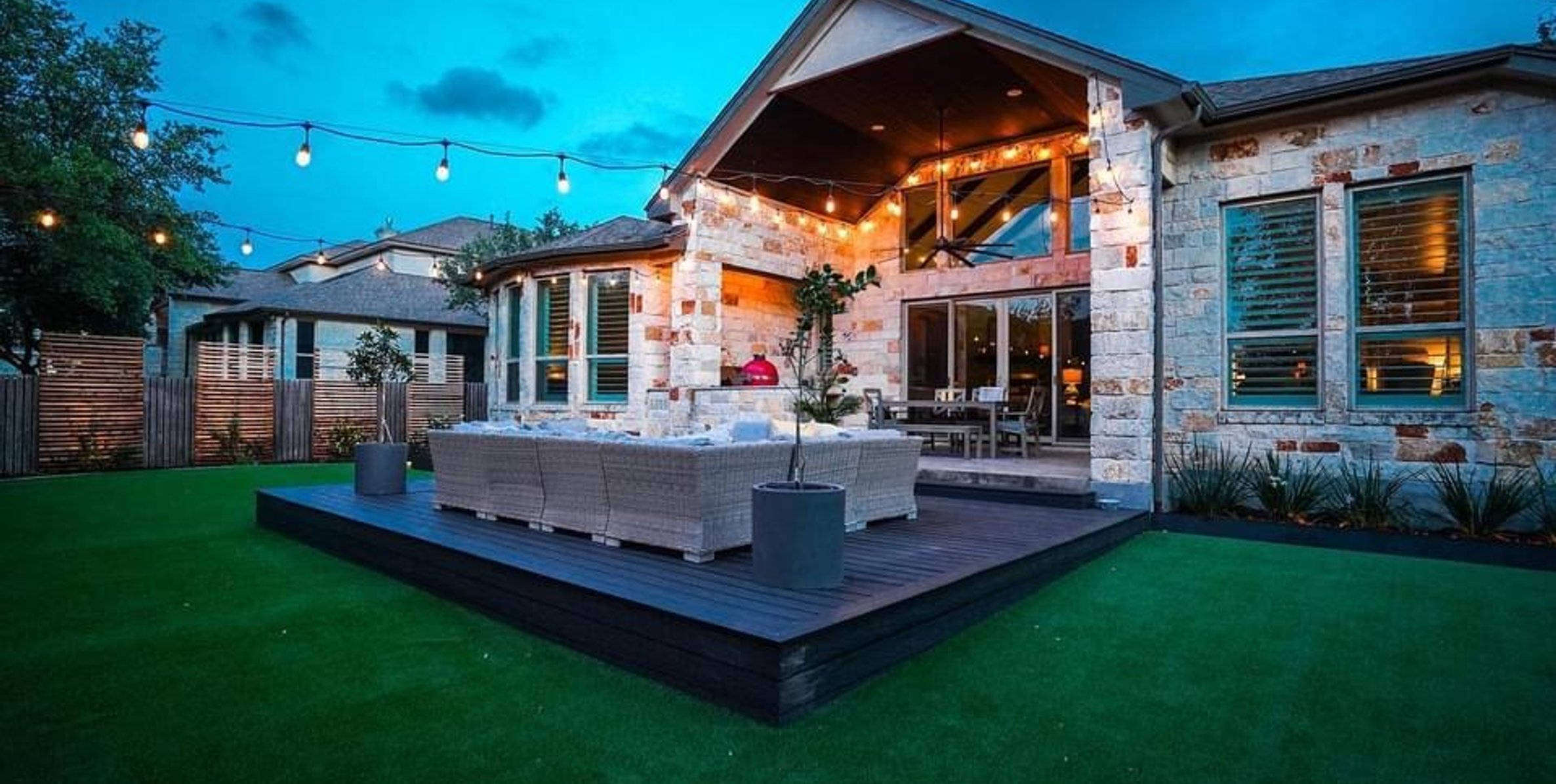 Composite deck with synthetic turf, string lights, and patio seating