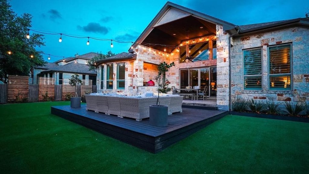 Finished custom deck with string lights over a turf patio in Bee Cave