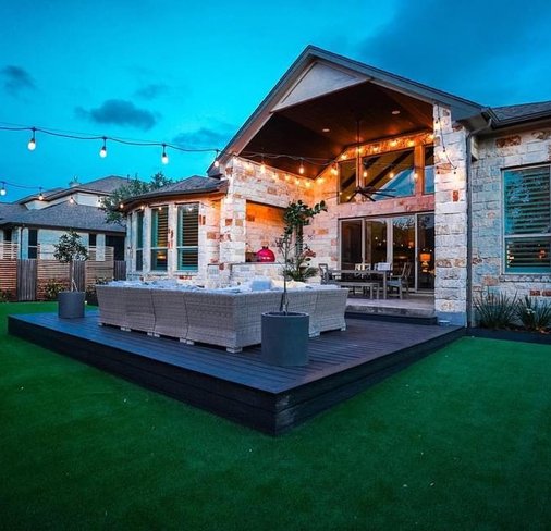 Bee Cave backyard with green turf, a deck, and a patio kept healthy by working irrigation