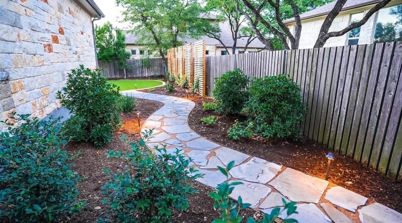Winding flagstone pathway through planting beds beside the turf island