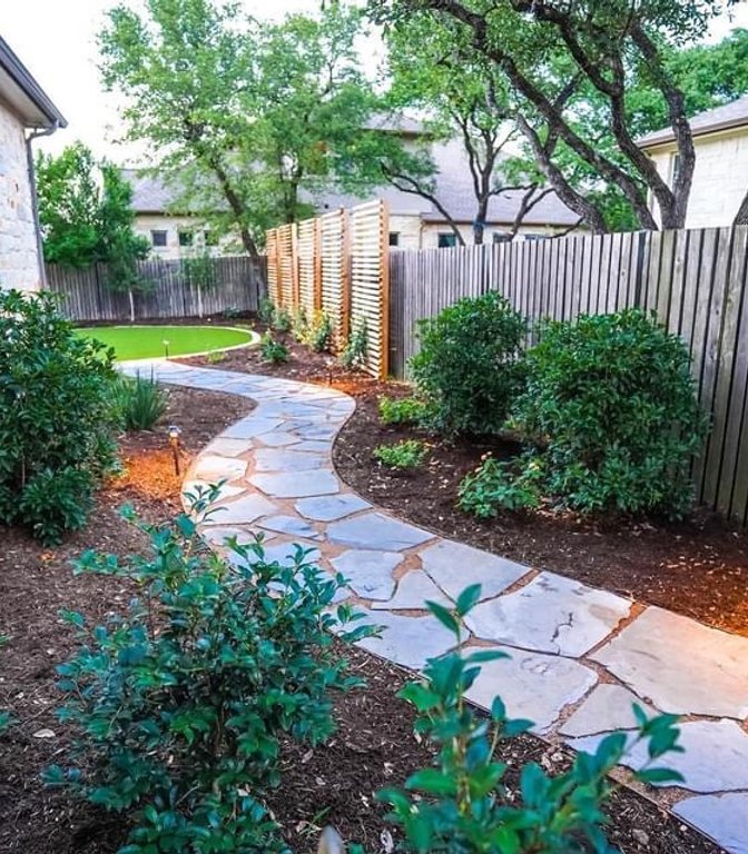 Planting beds layered along a Bee Cave cedar privacy screen