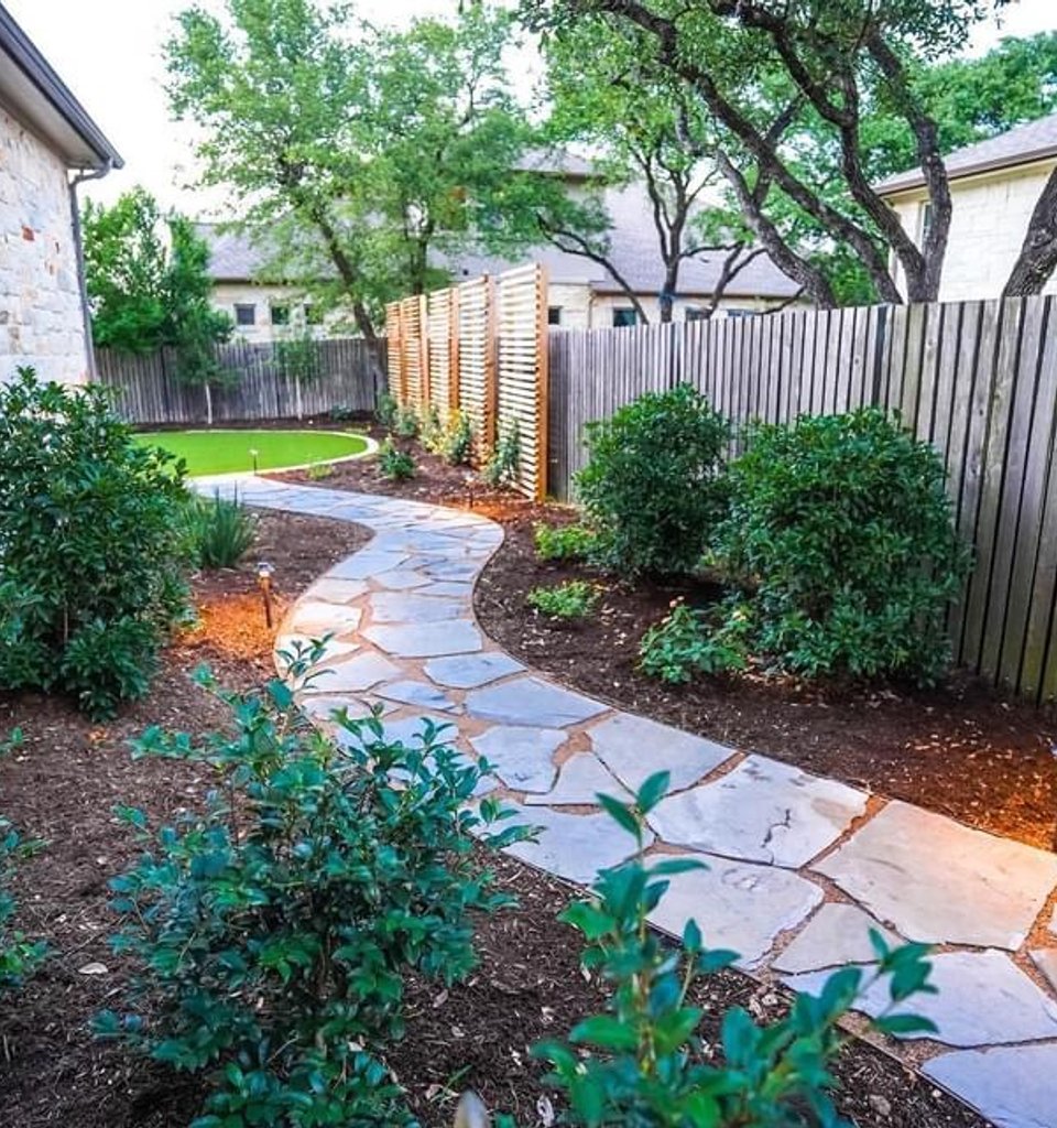 Bee Cave backyard with planting beds along a flagstone pathway under the oaks