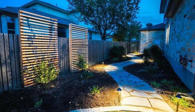 Path lighting along a flagstone walkway with privacy screens in a Bee Cave backyard