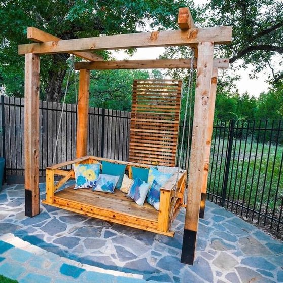 Pergola with a hanging swing over a flagstone patio and planters in a Bee Cave backyard