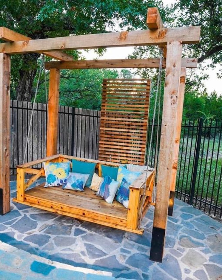 Bee Cave backyard with a pergola swing, flagstone patio, and planters
