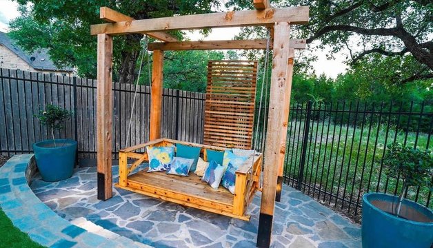 Bee Cave backyard living space with a pergola swing, flagstone patio, and planters