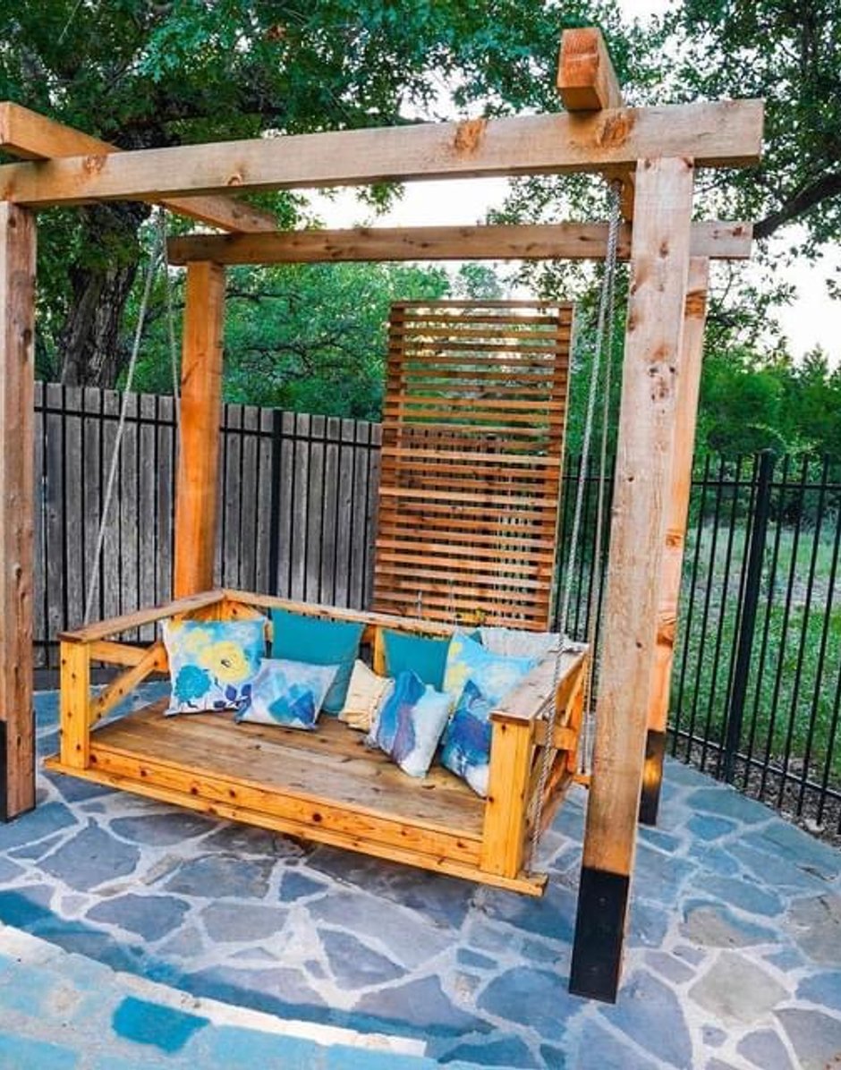 Cedar pergola framing a hanging bed swing on a circular flagstone patio