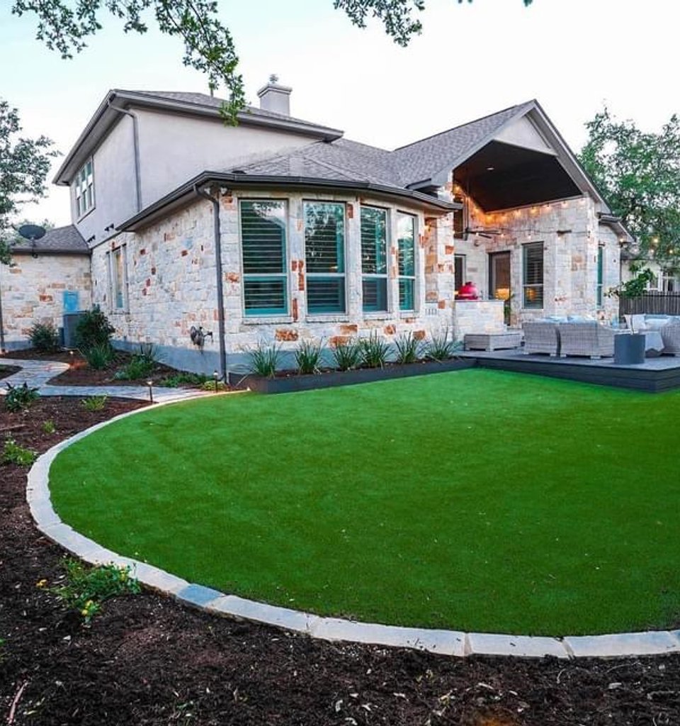 Bee Cave lawn edged with a stone border beside a deck and privacy screen