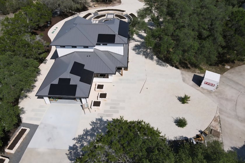 Aerial view of a designed Hill Country estate landscape in Driftwood with stone raised beds, paver walkways, and planting laid out to a master plan