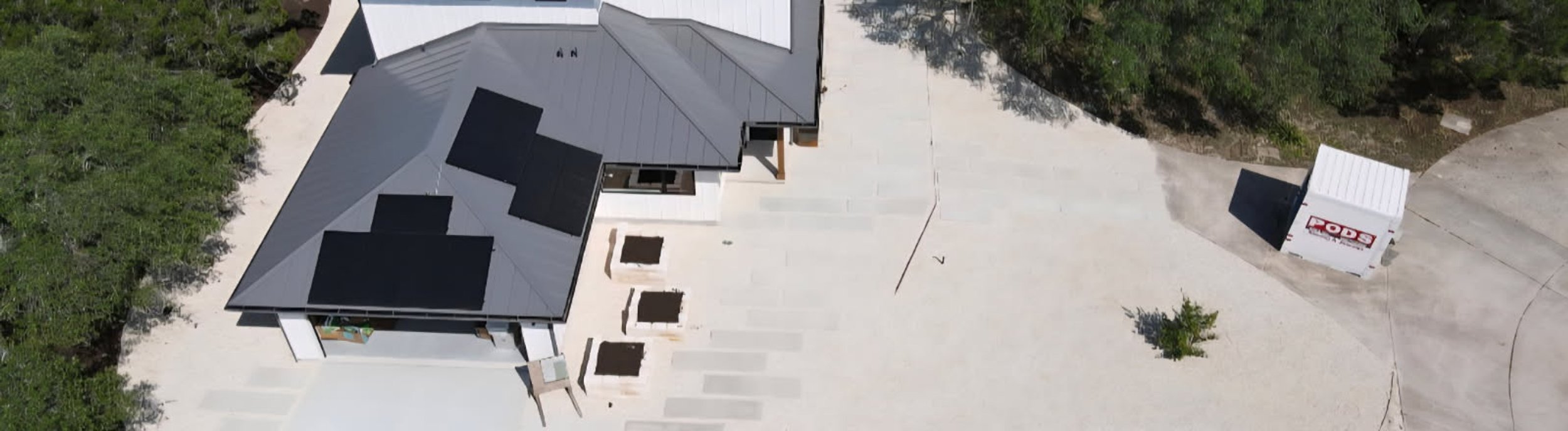 Aerial view of a designed Hill Country estate landscape in Driftwood with stone raised beds, paver walkways, and planting laid out to a master plan