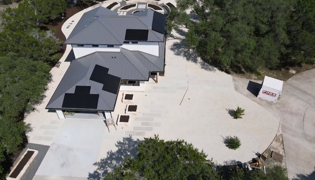 Aerial view of a graded Driftwood estate yard with raised beds laid out around the house