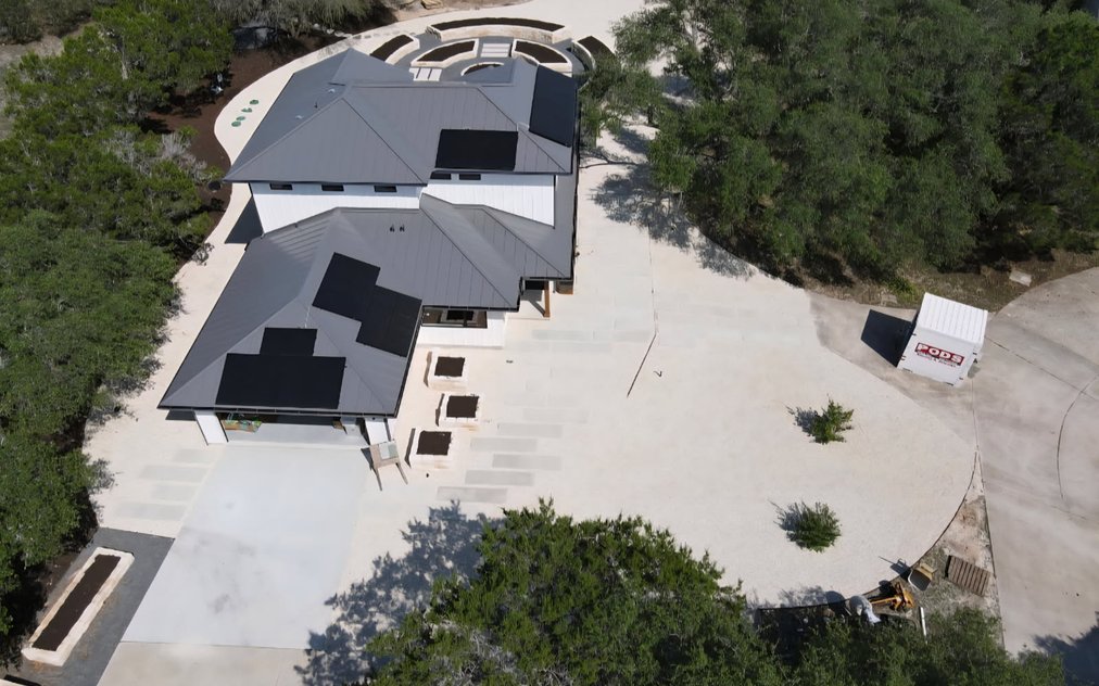 Aerial view of a designed Hill Country estate landscape in Driftwood with stone raised beds, paver walkways, and planting laid out to a master plan