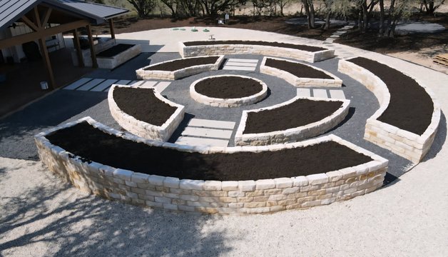 Driftwood estate with raised limestone beds, stone pavers, and a formal walkway built from a single master plan