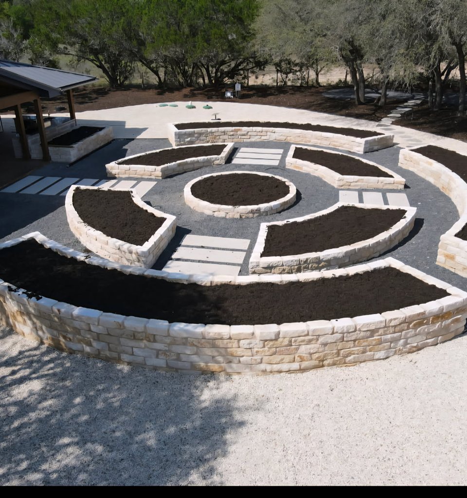 Driftwood garden estate with raised limestone beds and a stone paver walkway