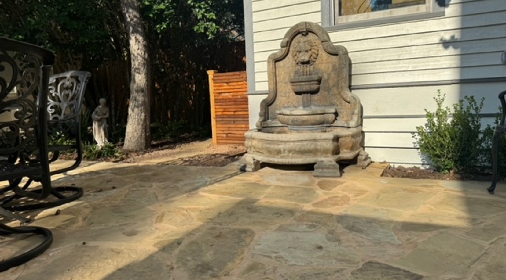 Cream flagstone patio with a fountain and iron furniture