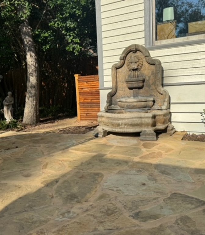Flagstone patio with a wood privacy screen and iron furniture in a garden setting