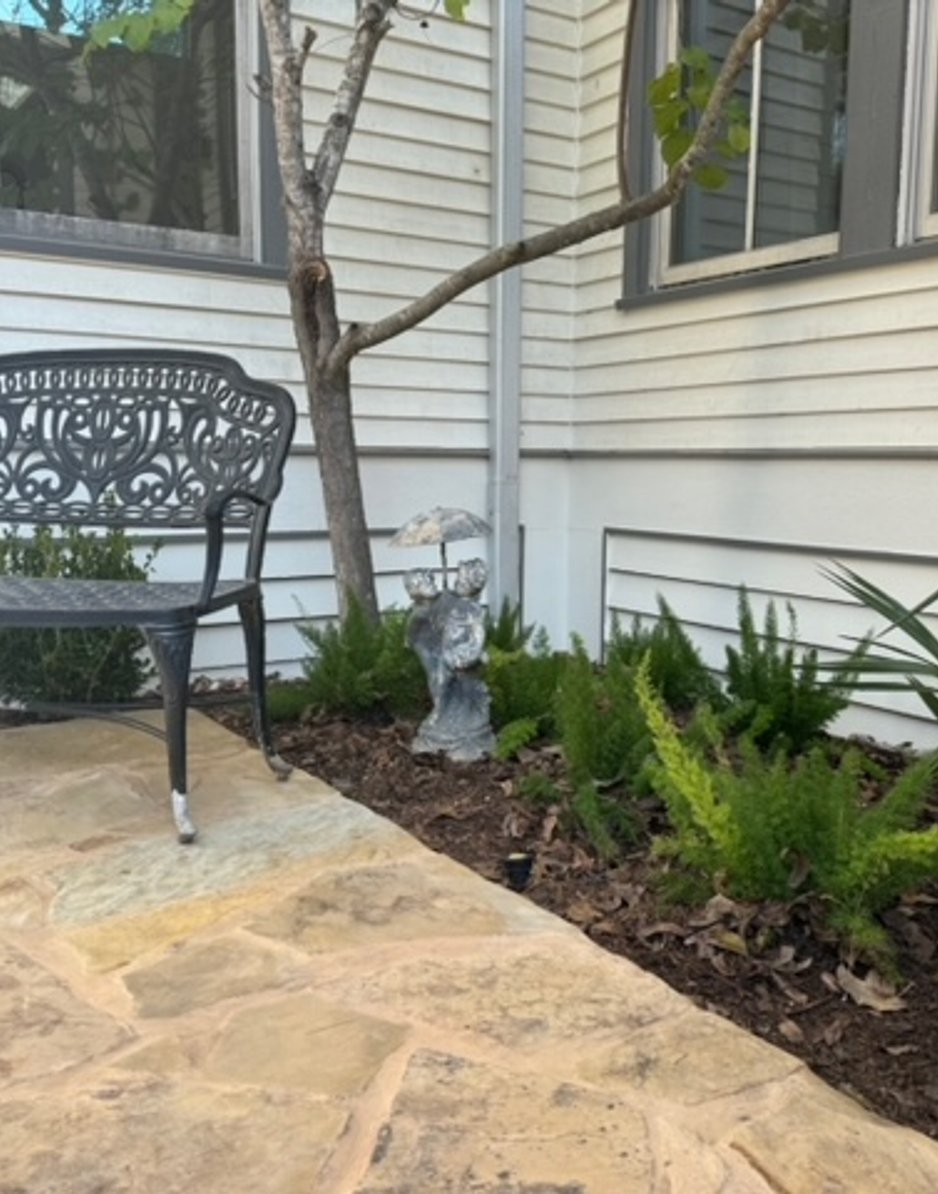 Iron bench set into a flagstone patio beside a garden bed