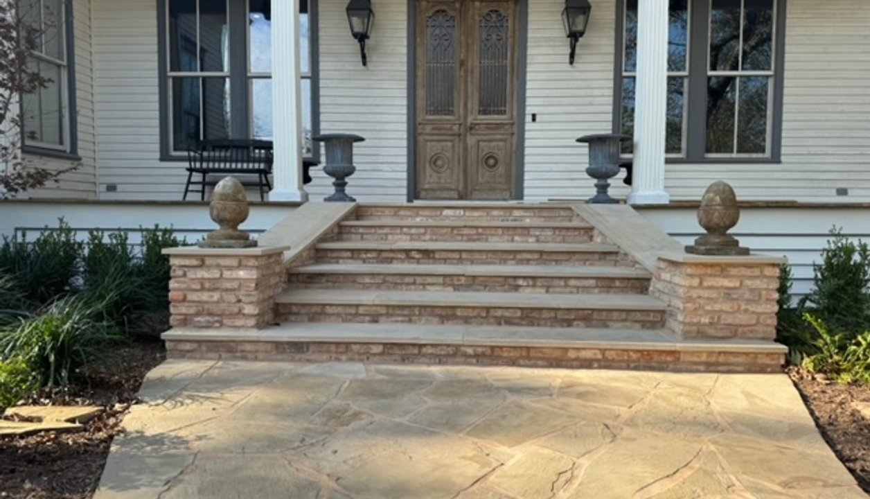 Flagstone walkway with brick steps winding through garden beds at a Fayetteville home