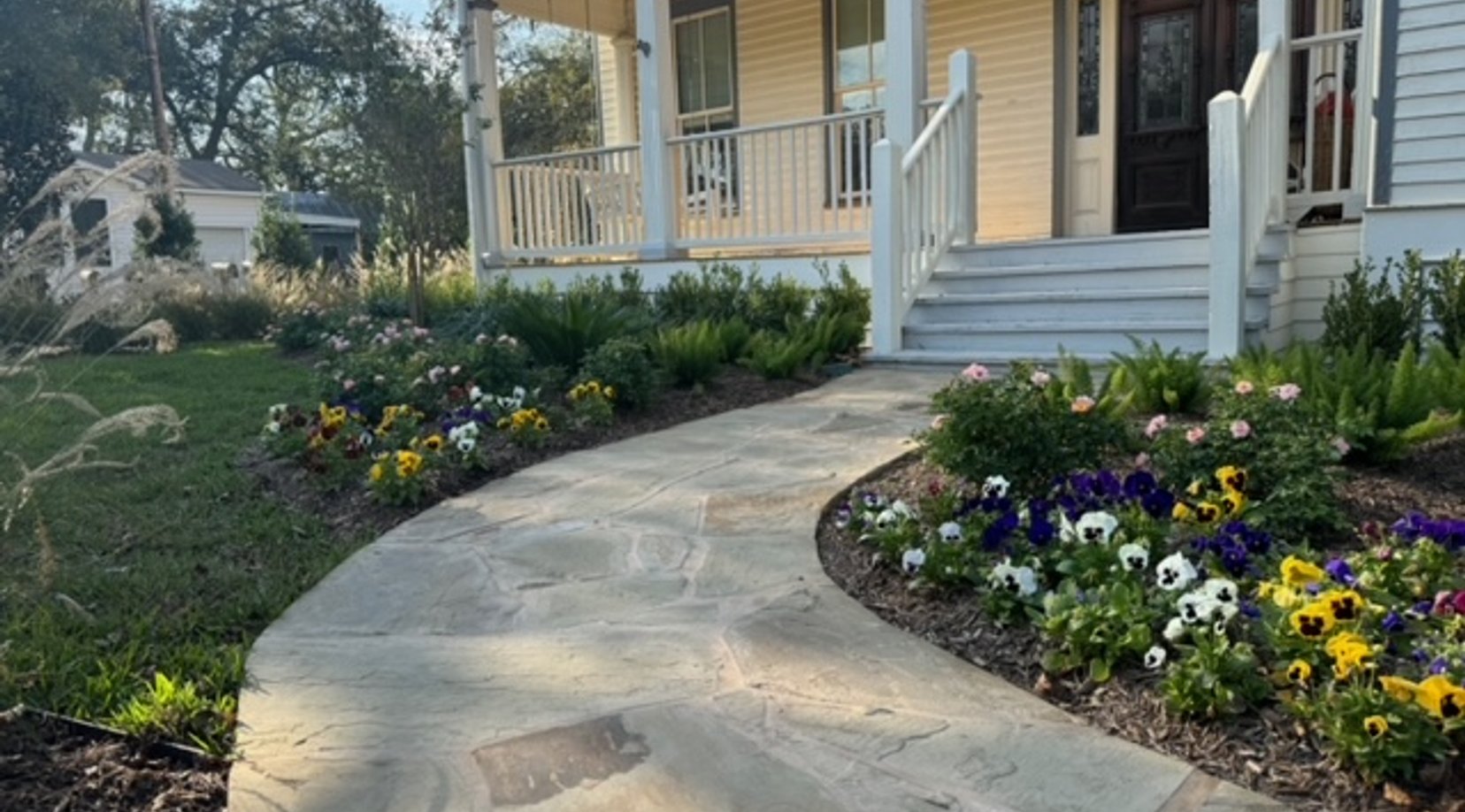 Flagstone walkway flanked by flower beds and lawn