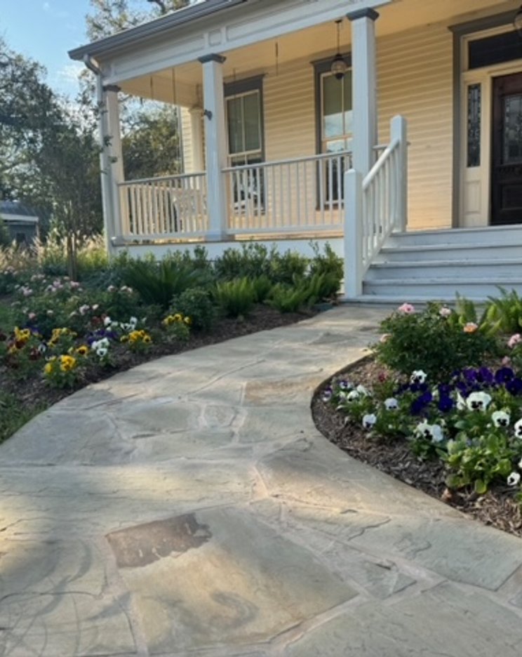 Green lawn bordered by flagstone walkway and flower beds at a garden-style yard