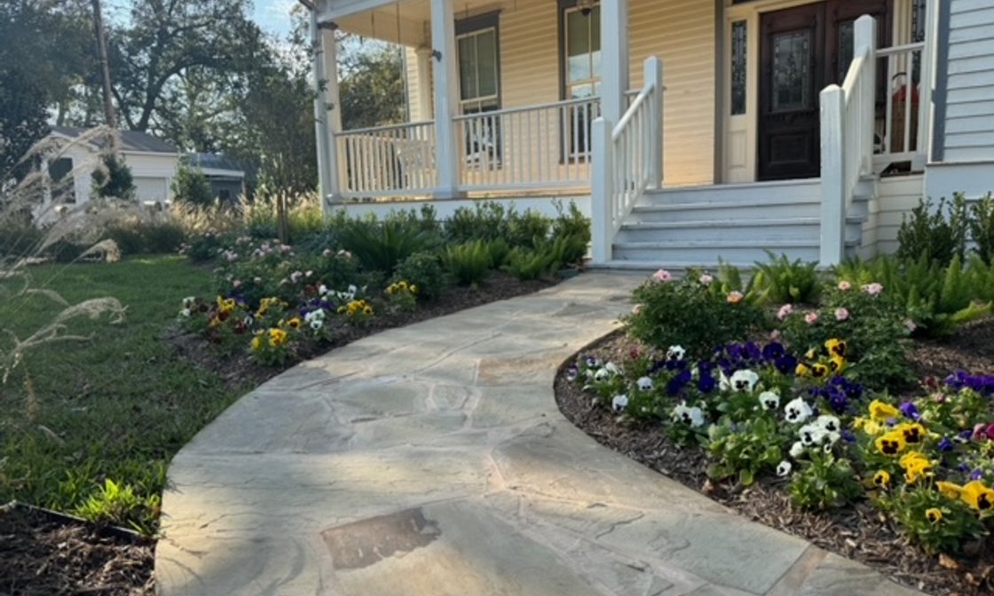 Austin landscape with a stone flagstone walkway, flower beds, and lawn