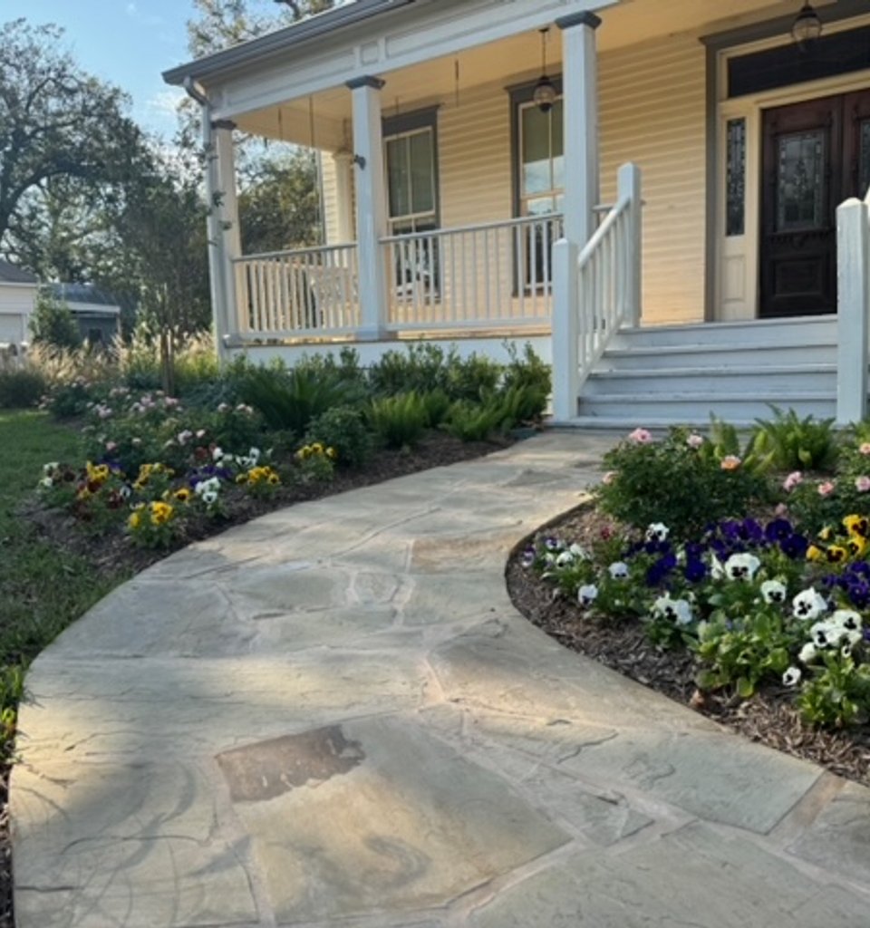 Garden-style yard with a green lawn, flagstone walkway, and full flower beds