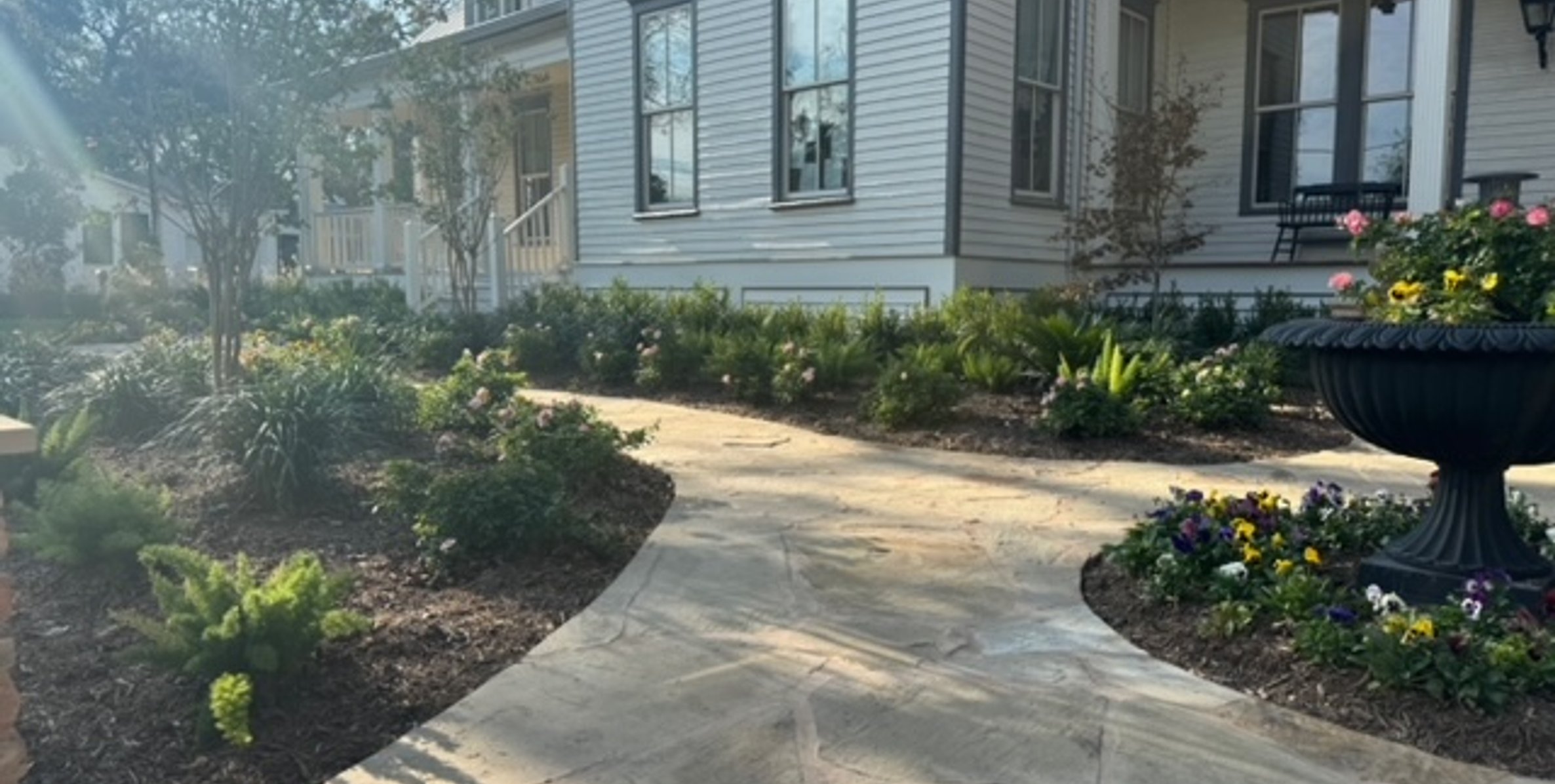 Flagstone walkway passing a circular accent bed centered on a decorative stone urn