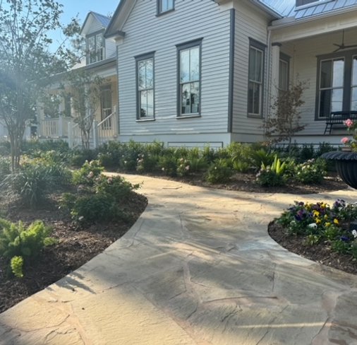 Freshly mulched garden beds along a flagstone walkway in a Central Texas garden