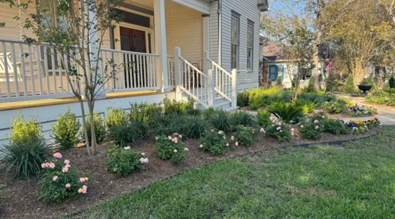 Densely planted flower beds bordering a manicured lawn