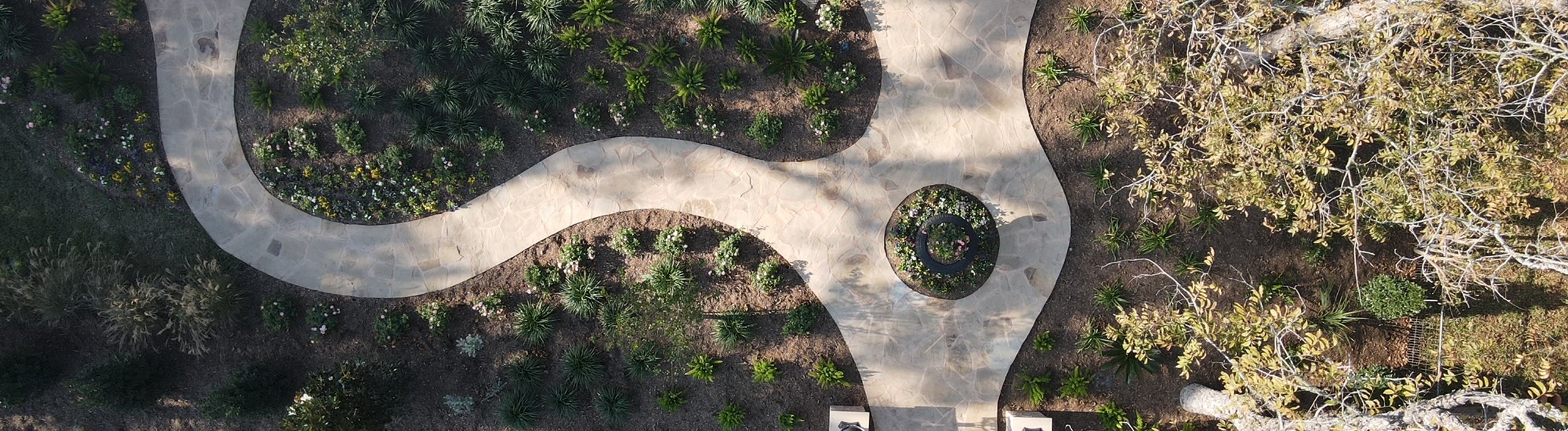 Aerial view of a layered Fayetteville, TX garden with flagstone walkway and densely planted beds by Thrive Landscape and Design