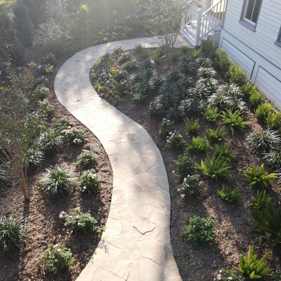 Custom home with a new flagstone front walkway and layered garden beds at a Fayetteville property