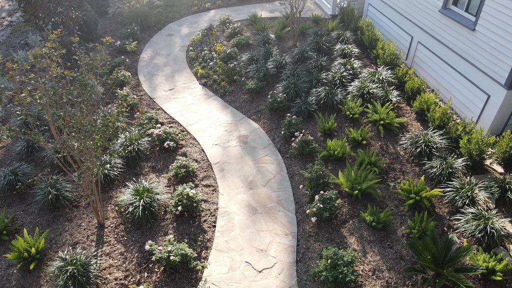 Finished mulched beds framing a walkway and lawn at a Central Texas property
