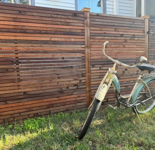 Healthy green lawn along a wood fence at a garden-style property