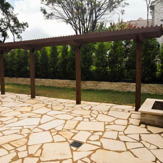 Light flagstone patio with a fire pit under a pergola at a Lakeway home in West Austin