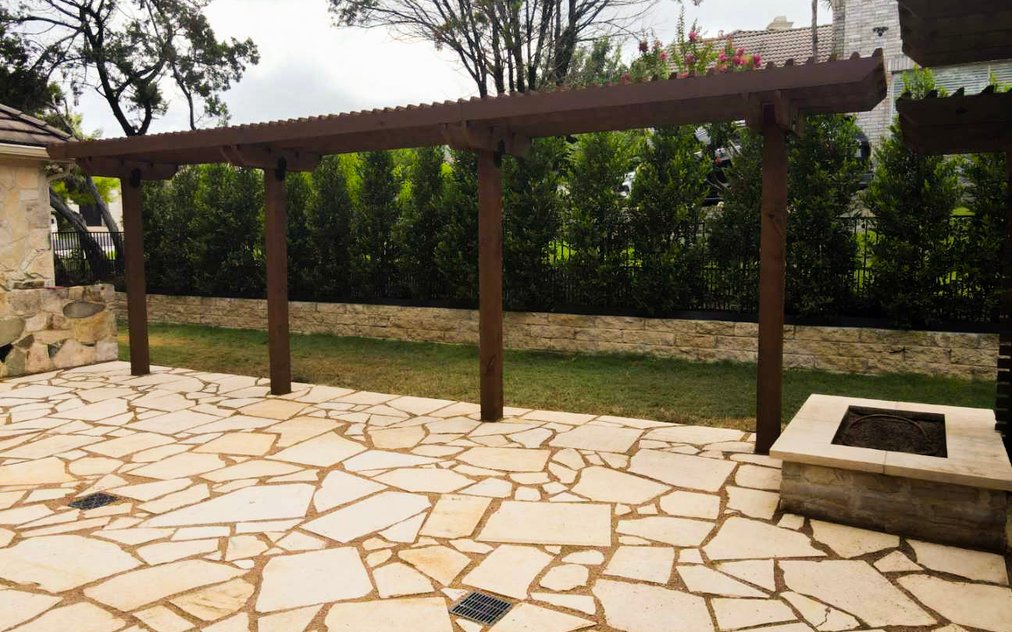 Cedar pergola shading a flagstone patio and fire pit in a Lakeway backyard near Austin