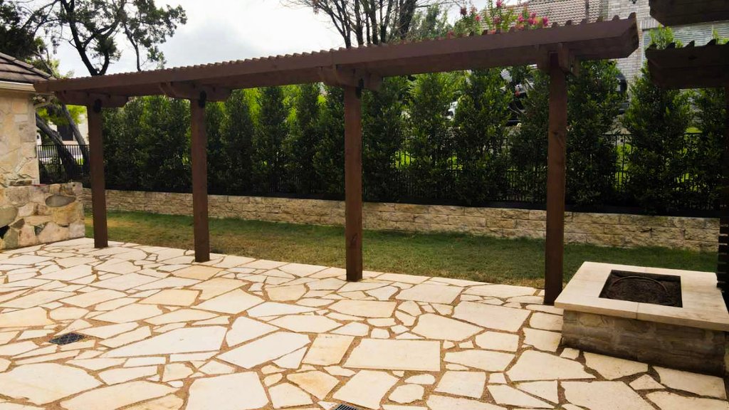 Gas fire pit set into a flagstone patio under a pergola at a Lakeway home