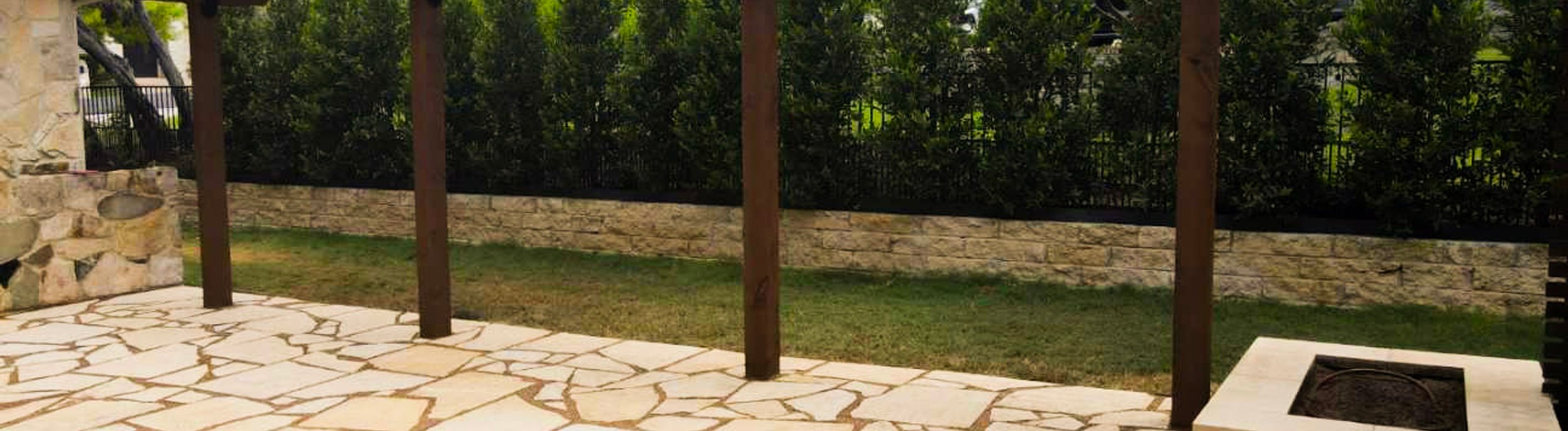 Cedar pergola shading a flagstone patio and fire pit in a Lakeway backyard near Austin