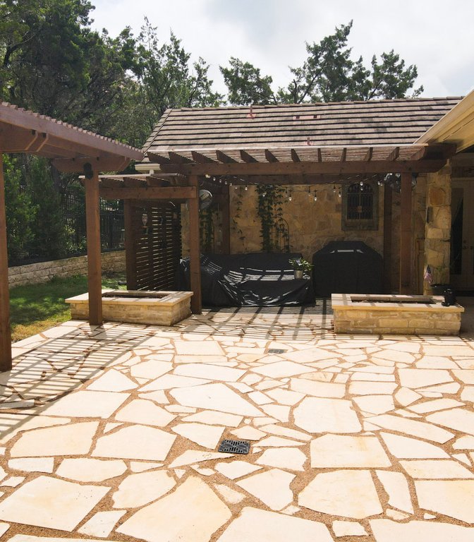 Custom deck and pergola over a flagstone patio with stone planters in Lakeway