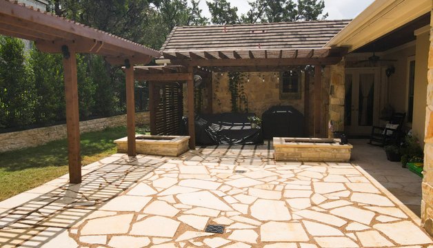 Flagstone patio with stone planters and a pergola in Lakeway, Austin